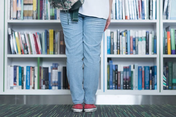 Famale student att välja bok att läsa i biblioteket — Stockfoto