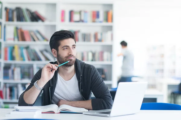 Studenten in de schoolbibliotheek met behulp van laptop voor onderzoek — Stockfoto