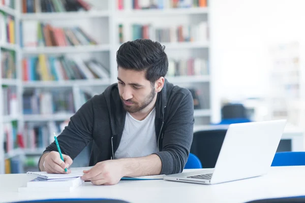 Estudante na biblioteca da escola usando laptop para pesquisa — Fotografia de Stock