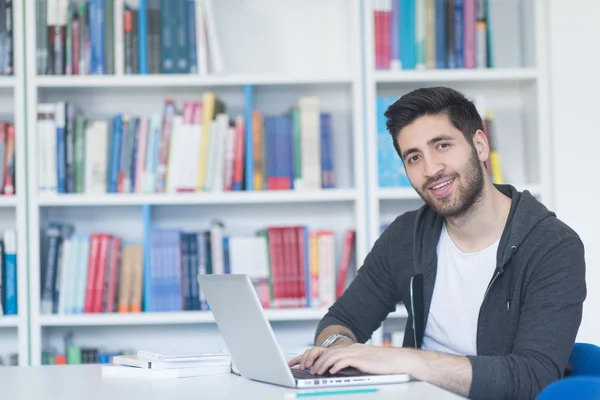 Estudante na biblioteca da escola usando laptop para pesquisa — Fotografia de Stock