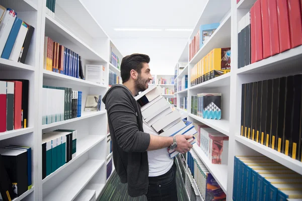 Studente che tiene molti libri nella biblioteca della scuola — Foto Stock