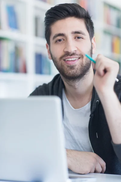 Estudiante en la biblioteca de la escuela usando el ordenador portátil para investigación — Foto de Stock