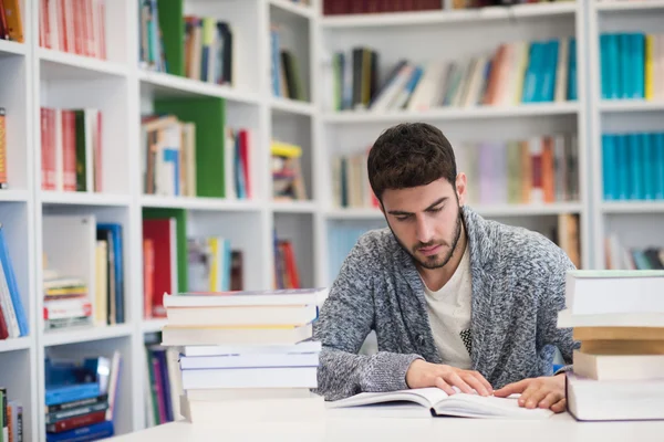 Retrato do estudante enquanto lê livro na biblioteca da escola — Fotografia de Stock