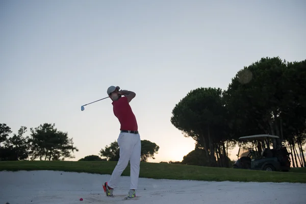 Golfista batendo um bunker de areia tiro no pôr do sol — Fotografia de Stock