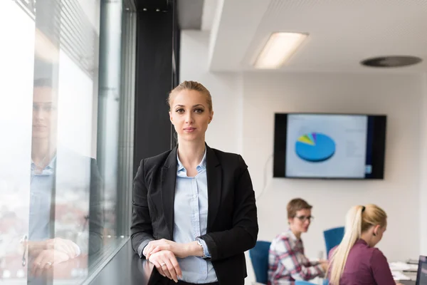 Porträtt av ung affärskvinna på kontoret med team på möte — Stockfoto