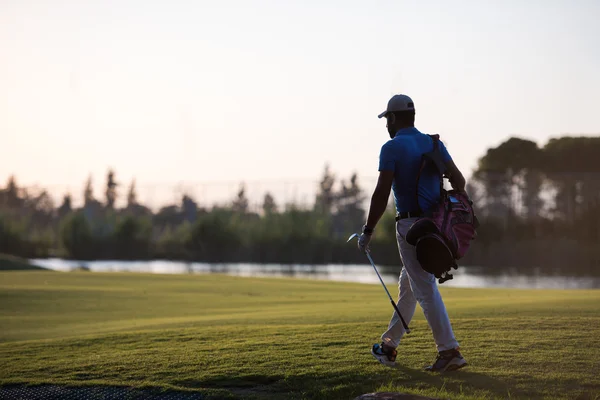 Golfista che cammina e porta borsa da golf al bellissimo tramonto — Foto Stock