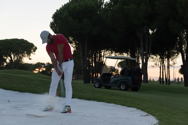 Golfista batendo um bunker de areia tiro no pôr do sol — Fotografia de Stock