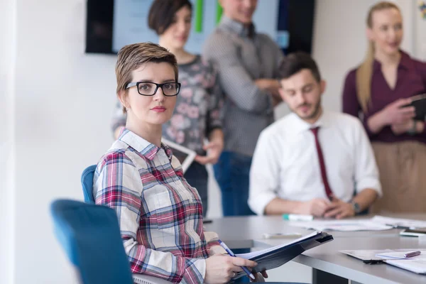 Porträtt av ung affärskvinna på kontoret med team på möte — Stockfoto