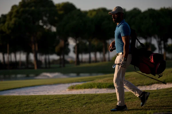 Golfista chůzi a nést brašnu na krásný západ slunce — Stock fotografie