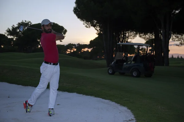 Golfista golpeando un tiro bunker de arena en la puesta del sol —  Fotos de Stock