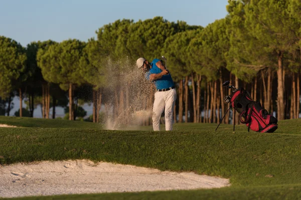 Golfer schlägt bei Sonnenuntergang in Sandbunker ein — Stockfoto