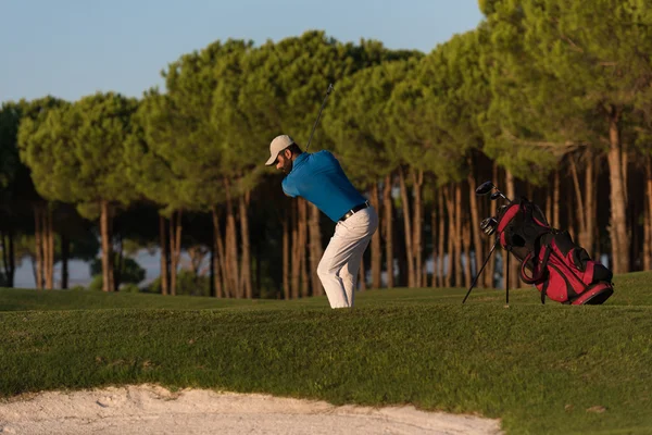 Golfista batendo um bunker de areia tiro no pôr do sol — Fotografia de Stock