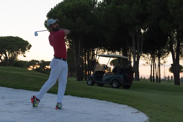 Golfista batendo um bunker de areia tiro no pôr do sol — Fotografia de Stock