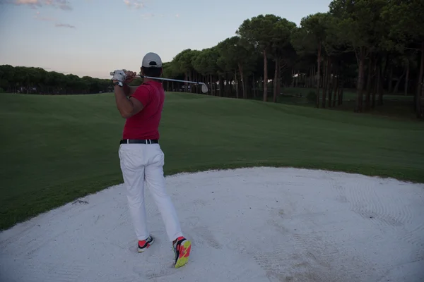 Golfista batendo um bunker de areia tiro no pôr do sol — Fotografia de Stock