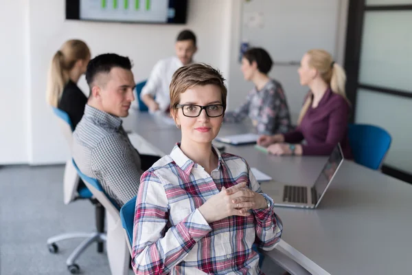 Porträtt av ung affärskvinna på kontoret med team på möte — Stockfoto