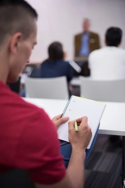 Estudante do sexo masculino tomar notas em sala de aula — Fotografia de Stock