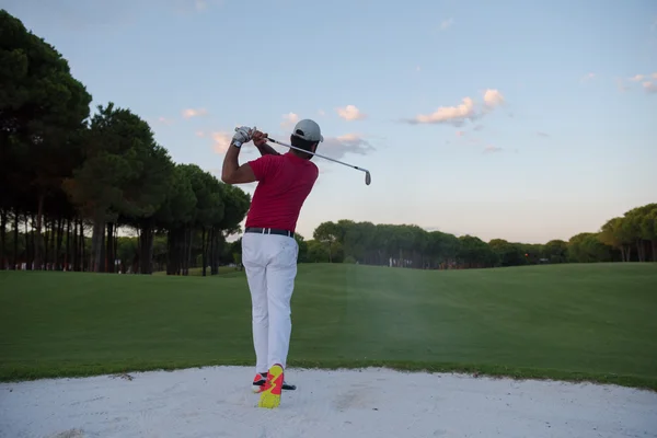 Golfspelare slår en sand bunker skott på sunset — Stockfoto