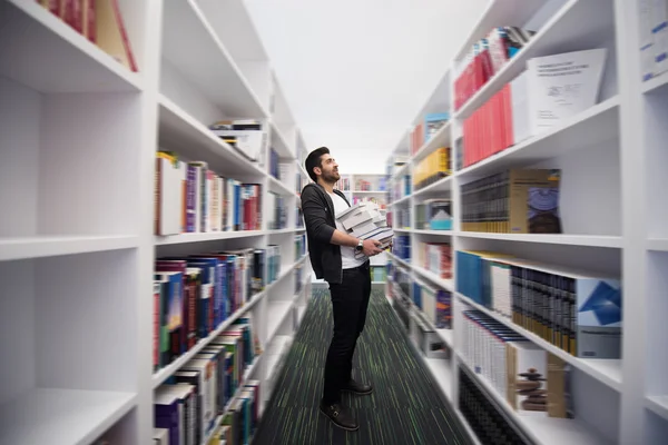 Student holding lot of books in school library — Stock Photo, Image