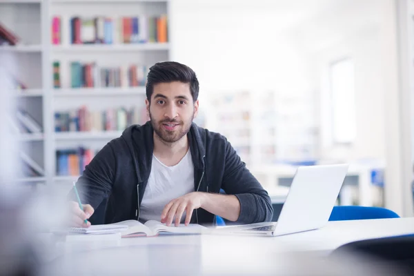 Estudiante en la biblioteca de la escuela usando el ordenador portátil para investigación —  Fotos de Stock