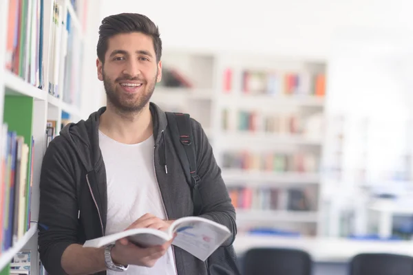 Portrait of student while reading book  in school library — Stock Photo, Image