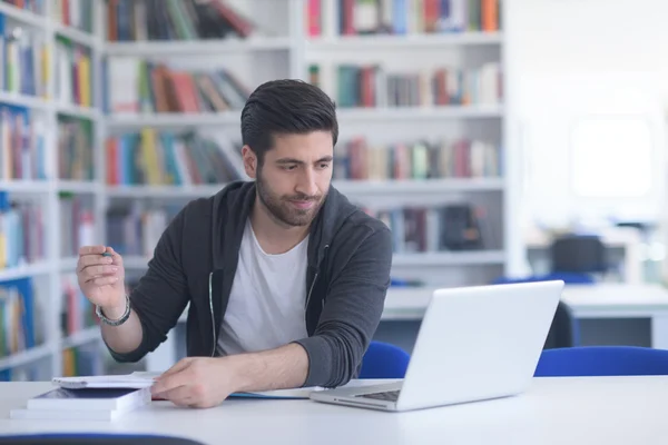 Estudante na biblioteca da escola usando laptop para pesquisa — Fotografia de Stock