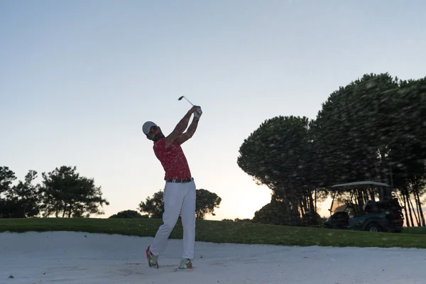 Golfista golpeando un tiro bunker de arena en la puesta del sol —  Fotos de Stock