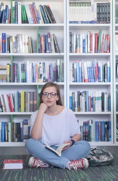 Vrouwelijke student selecteren boek om te lezen in de bibliotheek — Stockfoto