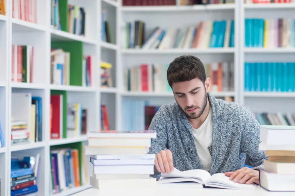 Retrato do estudante enquanto lê livro na biblioteca da escola — Fotografia de Stock