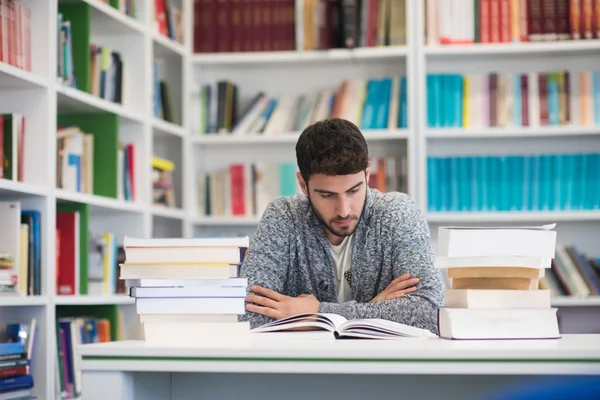 Retrato do estudante enquanto lê livro na biblioteca da escola — Fotografia de Stock