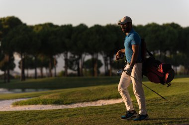 yürüyüş ve güzel günbatımı golf çantası taşıyan golfçü