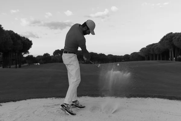 Golfista uderzanie piasku bunkra strzał na zachód słońca — Zdjęcie stockowe