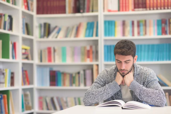 Retrato do estudante enquanto lê livro na biblioteca da escola — Fotografia de Stock