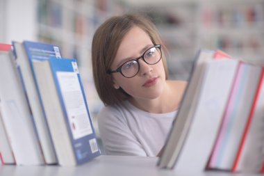 kitaplıkta okumak için kitap seçme kız öğrencinin portresi