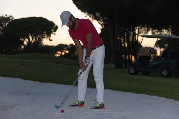 Golfer schlägt bei Sonnenuntergang in Sandbunker ein — Stockfoto