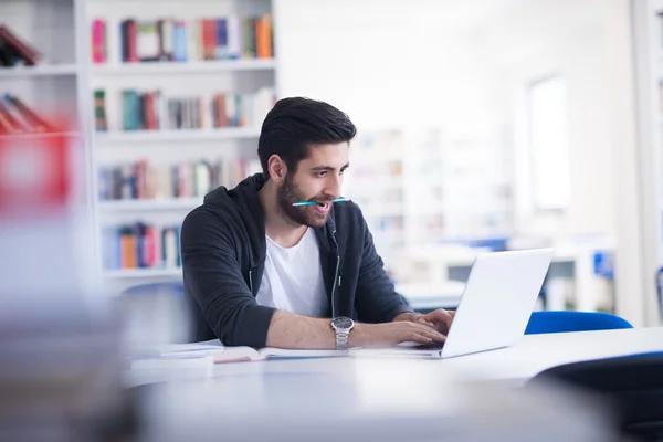 Estudiante en la biblioteca de la escuela usando el ordenador portátil para investigación —  Fotos de Stock