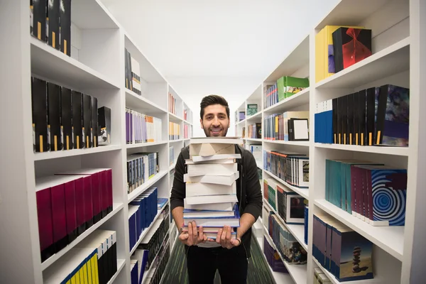 Studente che tiene molti libri nella biblioteca della scuola — Foto Stock