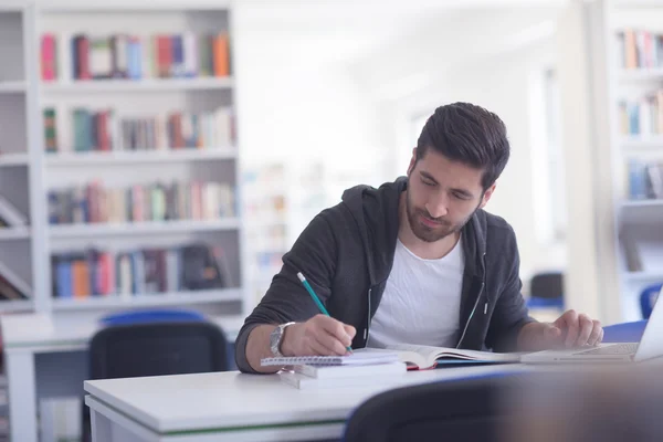 Estudiante en la biblioteca de la escuela usando el ordenador portátil para investigación — Foto de Stock