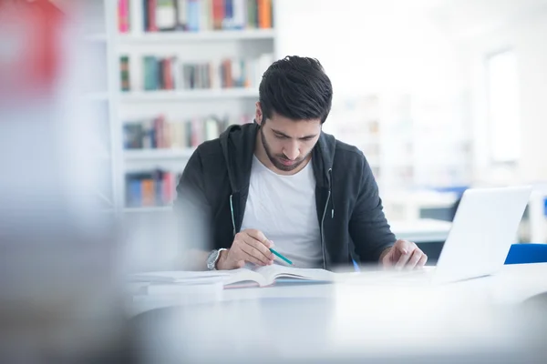 Studenten in de schoolbibliotheek met behulp van laptop voor onderzoek — Stockfoto