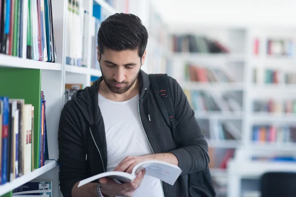 Ritratto dello studente mentre legge il libro nella biblioteca scolastica — Foto Stock