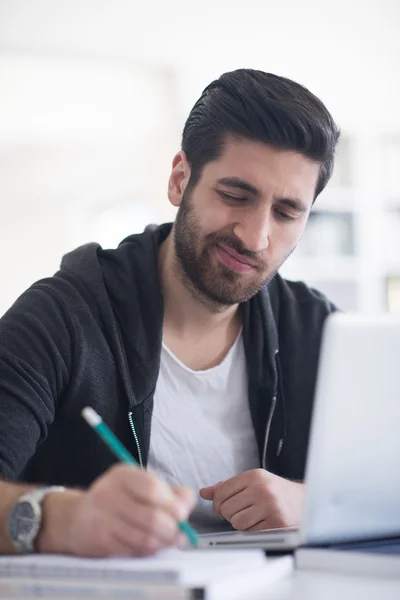 Estudiante en la biblioteca de la escuela usando el ordenador portátil para investigación — Foto de Stock