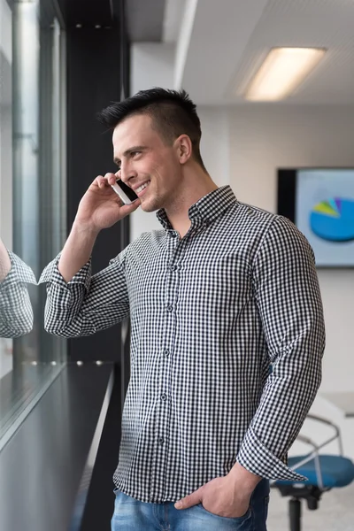 Молодой бизнесмен выступает на смартфоне в офисе — стоковое фото