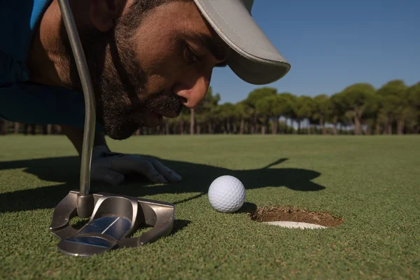 Golfspieler bläst Ball in Loch — Stockfoto