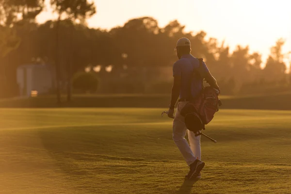 Golfista chůzi a nést brašnu na krásný západ slunce — Stock fotografie