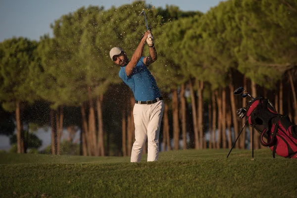 Golfer raken van een zand bunker shot op zonsondergang — Stockfoto