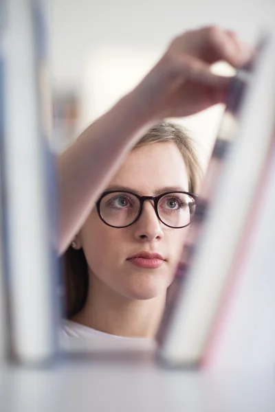 Portrait of famale student selecting book to read in library — Stock Photo, Image