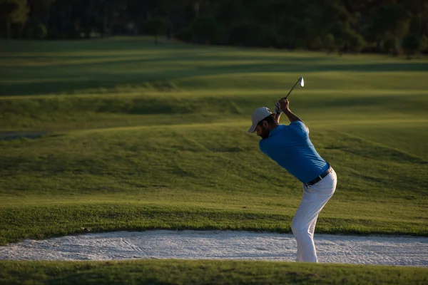 Golfista batendo um bunker de areia tiro no pôr do sol — Fotografia de Stock