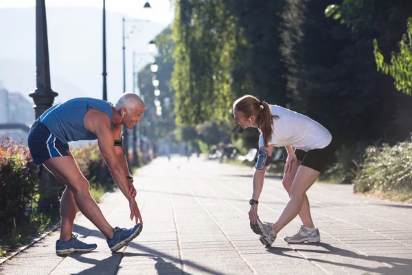 Couple warming up and stretching before jogging — Stock Photo, Image