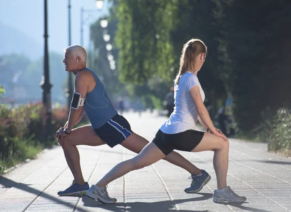 Couple warming up and stretching before jogging — Stock Photo, Image