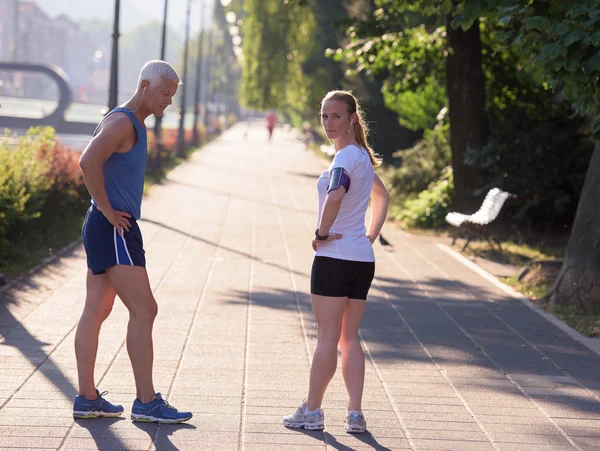 Couple warming up and stretching before jogging — Stock Photo, Image