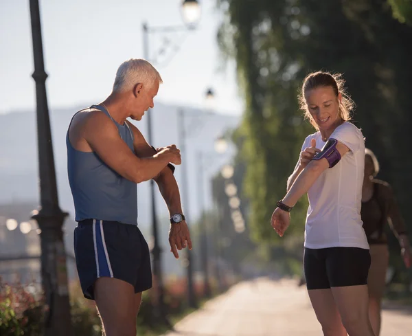 Jogging coppia pianificazione percorso in esecuzione e la musica impostazione — Foto Stock